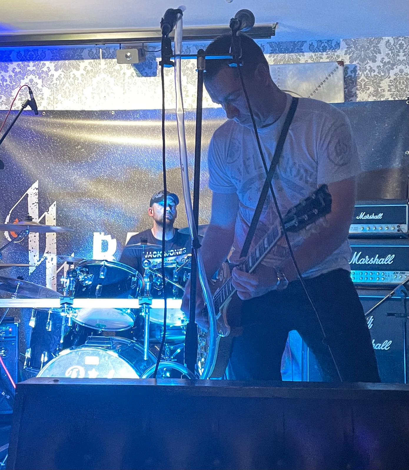 Backburner live — guitarist and drummer on stage with blue lights